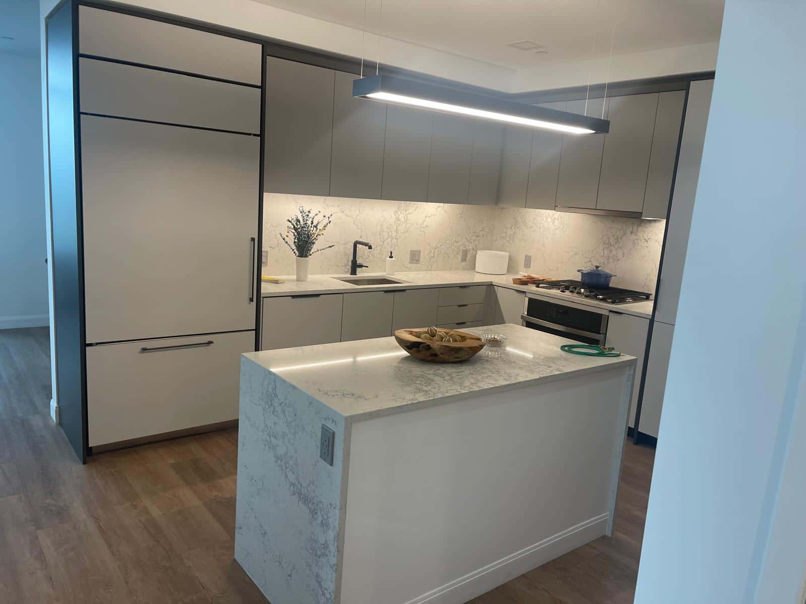 Modern kitchen with a marble waterfall island and tiled backsplash