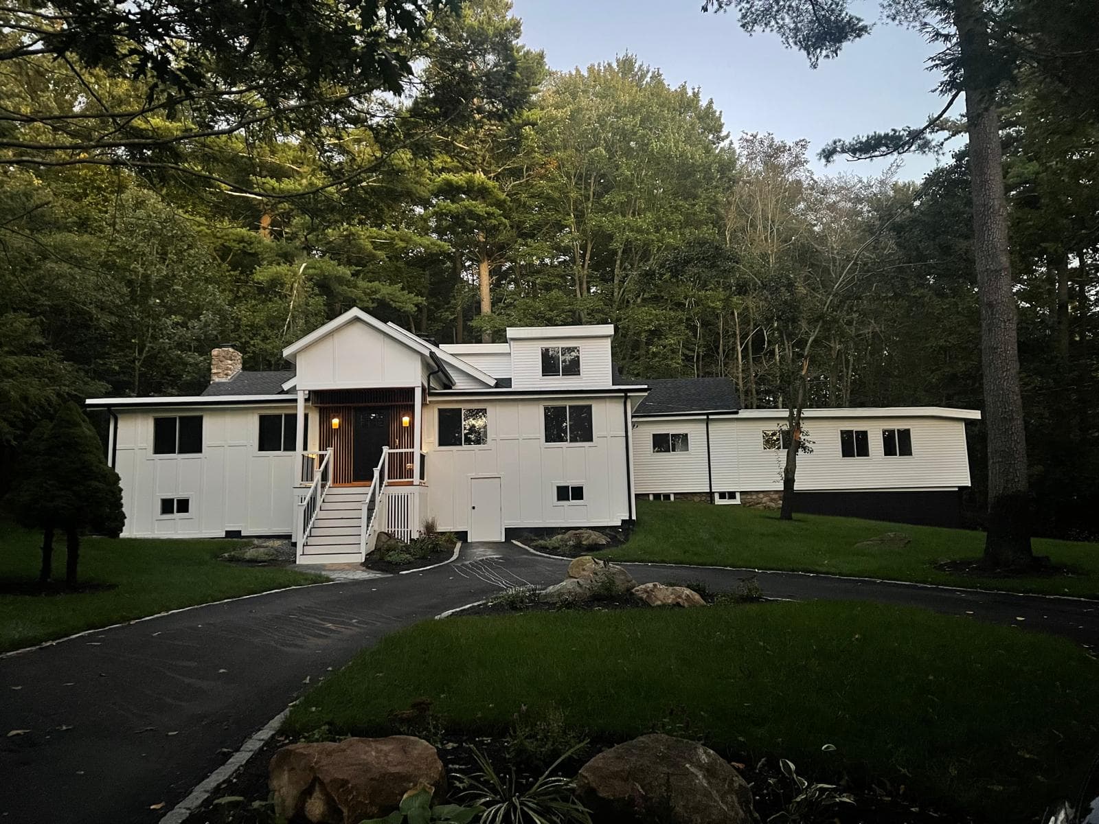 White custom home at dusk with a landscaped front yard and curved driveway