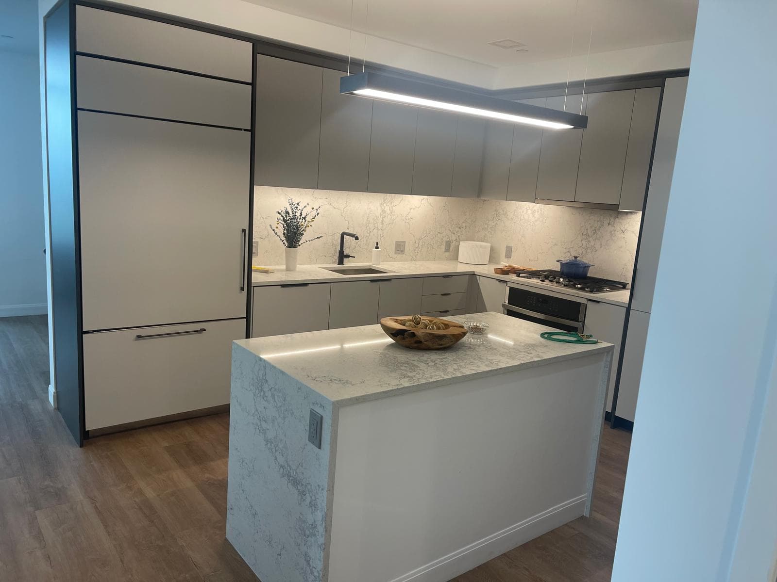Modern kitchen with a marble waterfall island and tiled backsplash